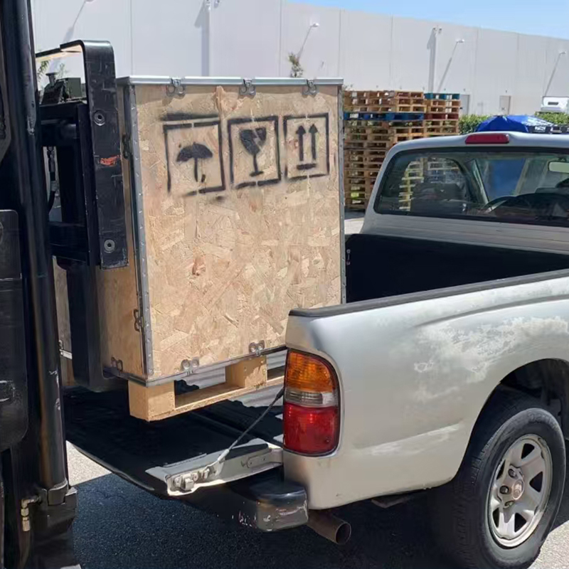 Wooden crate being loaded onto the back of a pickup truck